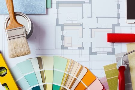 Painter and decorator work table with house project, color swatches, painting roller, brush and tools, top view